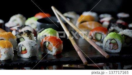 Sushi rolls arranged on a dark surface with chopsticks and soy sauce in a restaurant setting Sushi rolls arranged on a dark surface with chopsticks and soy sauce in a restaurant setting 137717165