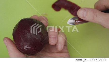 Peeling beetroot in a kitchen on a green cutting board in the afternoon with a simple knife 137717185