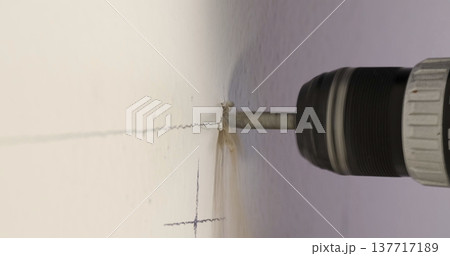 Drilling into a wall with a power tool to create a hole for installation during a home improvement project Drilling into a wall with a power tool to create a hole for installation during a home improvement project 137717189