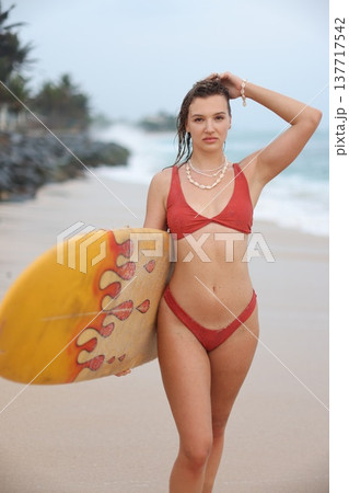 Professional Lifeguard Instructor In Red Swimwear Posing With Surfboard Against Seaside Background 137717542