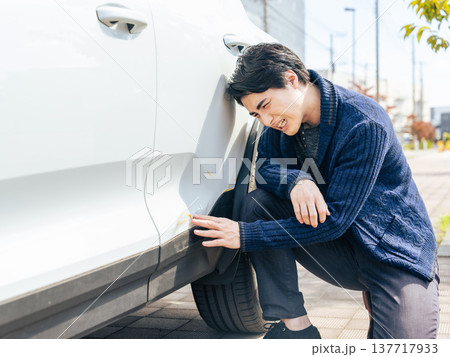 自動車のボディの傷が気になる男性ドライバー 自動車のボディの傷が気になる男性ドライバー 137717933