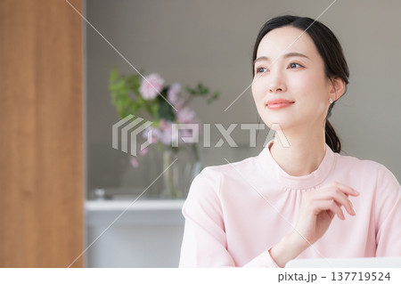 デスクで座るパソコンの仕事をするピンクの服を着た綺麗な女性 137719524