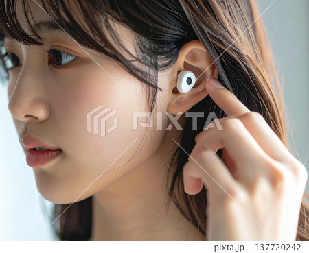 ワイヤレスイヤホンを付ける若い女性 137720242