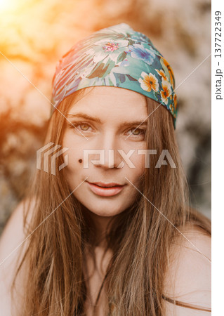 Woman portrait bandana wearing floral headscarf looks at camera outdoors during golden hour sunset light bohemian style Woman portrait bandana wearing floral headscarf looks at camera outdoors during golden hour sunset light bohemian style 137722349