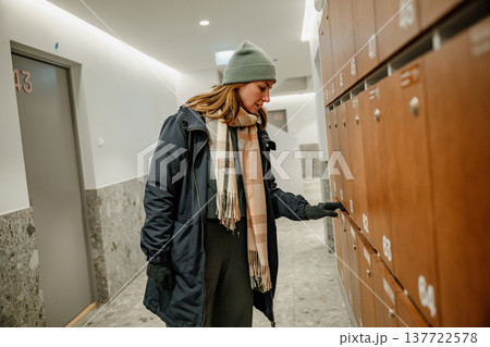 Woman checking mailboxes in an indoor hallway during the late afternoon Woman checking mailboxes in an indoor hallway during the late afternoon 137722578