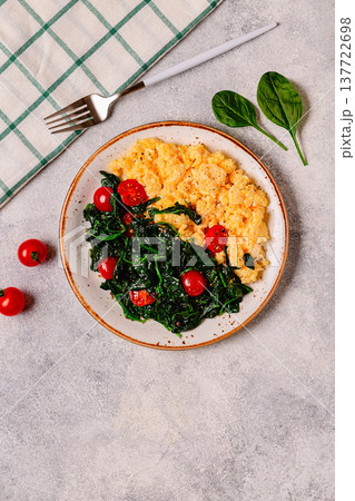 Cooked omelette and spinach with tomatoes on a light background 137722698