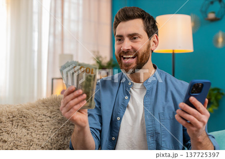 Man checking balance on smartphone, excited about received money, celebrating lottery or game win 137725397