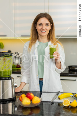 Middle-aged woman making green smoothie with blender in kitchen for healthy detox breakfast dieting Middle-aged woman making green smoothie with blender in kitchen for healthy detox breakfast dieting 137725456