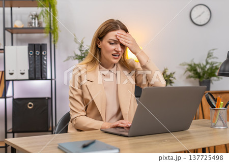 Businesswoman faces laptop system crash data loss holds head facepalm error pops up failure reaction Businesswoman faces laptop system crash data loss holds head facepalm error pops up failure reaction 137725498