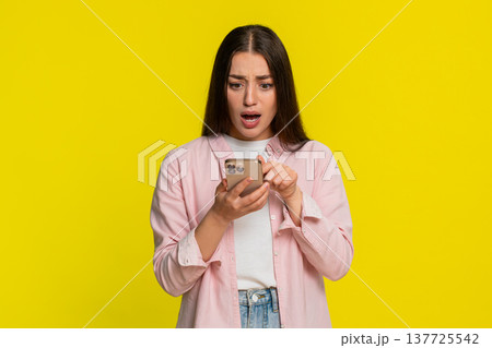 Woman panicking tapping smartphone screen reacting in fear after deleting something by mistake 137725542