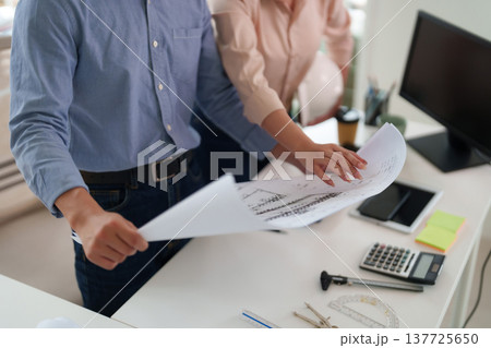 Architects engineers collaborate reviewing building blueprints construction plans modern office design team project development workspace professional discussion Architects engineers collaborate reviewing building blueprints construction plans modern office design team project development workspace professional discussion 137725650