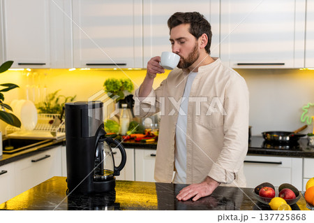 Middle-aged man enjoying fresh coffee aroma in home kitchen before breakfast morning with calm smile Middle-aged man enjoying fresh coffee aroma in home kitchen before breakfast morning with calm smile 137725868
