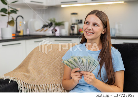 Young woman counts dollars cash money plans big purchase feels proud of savings salary and bonus Young woman counts dollars cash money plans big purchase feels proud of savings salary and bonus 137725958