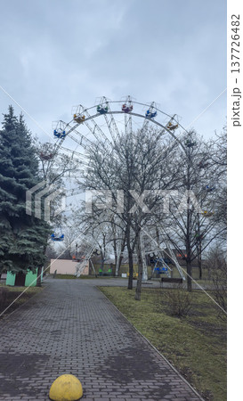 A Ferris wheel in the rays of the setting sun in a winter city park. A Ferris wheel in the rays of the setting sun in a winter city park. 137726482