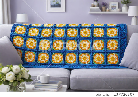 A knitted throw with a floral pattern on a sofa in a bright living room. AI A knitted throw with a floral pattern on a sofa in a bright living room. AI 137726507