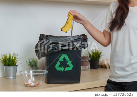 Waste Management. Woman discarding banana peel into recycling bin. 137726528
