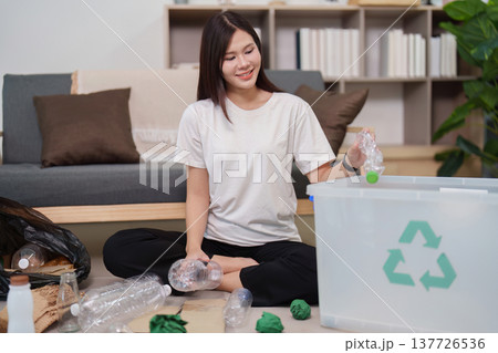 Sustainability. Young woman recycling plastic bottles at home for environmental responsibility. 137726536