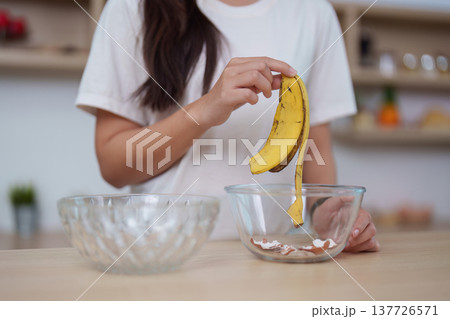 Healthy Lifestyle. Woman preparing to make a smoothie with banana in kitchen. 137726571