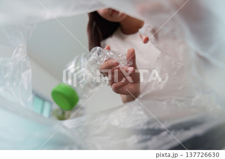 Sustainability. Woman recycling plastic bottle for eco-friendly living. 137726630