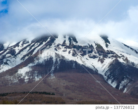 頂きを雲で覆われた雪解けが進む春の岩木山の斜面をクローズアップで捉えた自然風景 (青森県、弘前) 137726812