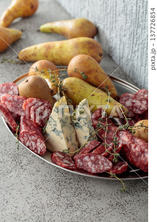 Blue cheese, dry-cured sausages, thyme and pears on a stone table. 137726854