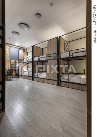 Modern Hostel Dormitory with Row of Wooden Bunk Beds 137727295