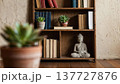 A minimalist bookshelf with books, plants, and a small Buddha statue, creating a peaceful and calming environment suitable for relaxation, reflection, and meditation. 137727876