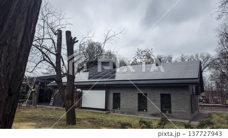 A modern building with solar panels on its roof in a city park. 137727943