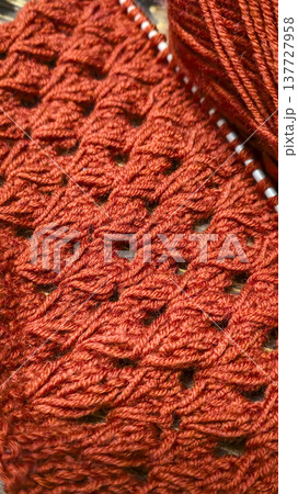 Knitting patterns with a raised pattern and yarn on a dark background Terracotta Knitting patterns with a raised pattern and yarn on a dark background Terracotta 137727958
