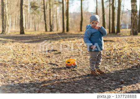 Happy baby child outdoor. Little toddler boy with toy car having fun on walk in park. Baby son smiling playing outdoor. Little child resting walking in nature. Little toddler child having fun on walk Happy baby child outdoor. Little toddler boy with toy car having fun on walk in park. Baby son smiling playing outdoor. Little child resting walking in nature. Little toddler child having fun on walk 137728888