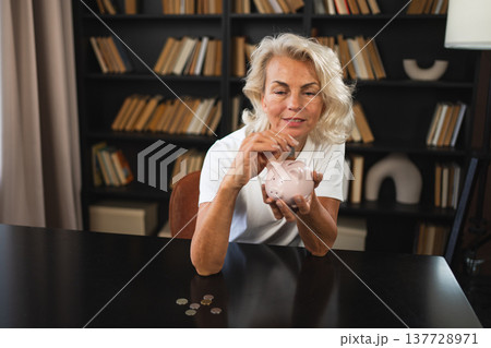 Saving money investment for future. Senior adult mature woman putting money coin in piggy bank. Old grandmother counting saving money planning retirement budget. Investment banking concept 137728971
