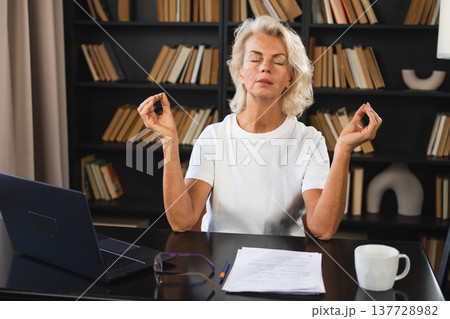 Yoga mindfulness meditation No stress keep calm. Middle aged woman practicing yoga at office. Woman taking break from work meditating relaxing. Mature lady doing breathing practice online yoga at work Yoga mindfulness meditation No stress keep calm. Middle aged woman practicing yoga at office. Woman taking break from work meditating relaxing. Mature lady doing breathing practice online yoga at work 137728982