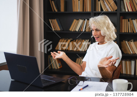 Video call. Happy middle aged senior woman sit with laptop talk on video call. Mature old senior lady having fun talking speaking online. Older generation modern tech usage Virtual meeting online chat Video call. Happy middle aged senior woman sit with laptop talk on video call. Mature old senior lady having fun talking speaking online. Older generation modern tech usage Virtual meeting online chat 137728984