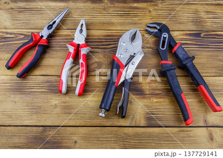Set of different pliers on wooden background. Top view Set of different pliers on wooden background. Top view 137729141