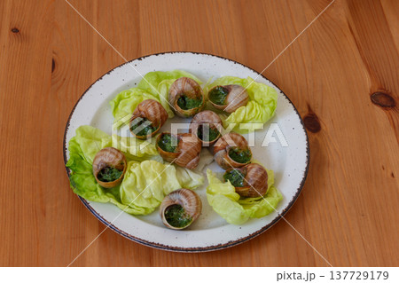 Escargots de Bourgogne (snails) seasoned with butter, parsley, garlic on wooden table 137729179