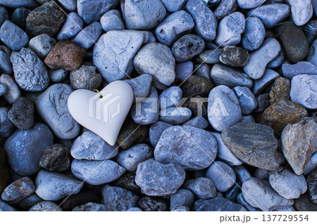 A figurine of a stone heart lies among the stones A figurine of a stone heart lies among the stones 137729554