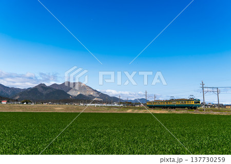藤原岳を背景に快晴の中を走る三岐鉄道三岐線の緑色車両 137730259