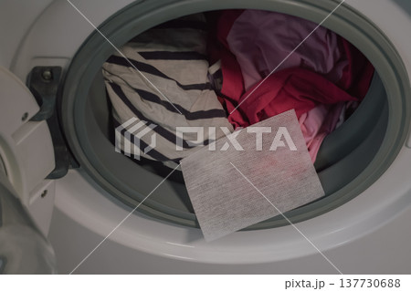 laundry risk concept: color catcher sheet inside washer with mixed brightly colored garments for protection 137730688