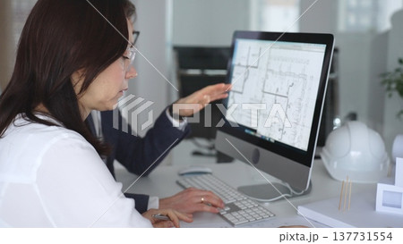Architects collaborating on building plans using computer aided design software and architectural models. Business and architecture concept Architects collaborating on building plans using computer aided design software and architectural models. Business and architecture concept 137731554