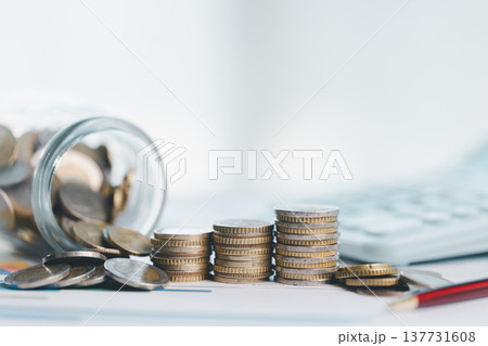 Coin jar and stacked coins beside calculator on financial documents, symbolizing savings, budgeting, accounting and investment planning for personal finance and business growth strategy. investment Coin jar and stacked coins beside calculator on financial documents, symbolizing savings, budgeting, accounting and investment planning for personal finance and business growth strategy. investment 137731608