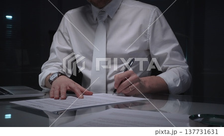 Business man signing a contract late in the office, closing a deal, or completing legal paperwork at deep night. Audit and overworking concepts 137731631