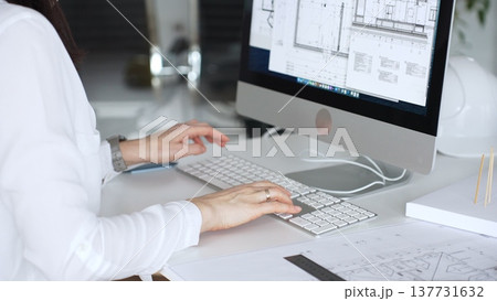 Architect working at desktop computer, checking blueprints and design plans for a new engineering project. Business and architecture concept Architect working at desktop computer, checking blueprints and design plans for a new engineering project. Business and architecture concept 137731632