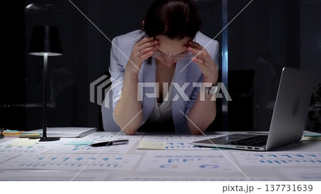Stressed business woman suffering from headache in dark office, hands on head experiencing burnout and fatigue during late night work, facing deadline pressure and financial difficulties Stressed business woman suffering from headache in dark office, hands on head experiencing burnout and fatigue during late night work, facing deadline pressure and financial difficulties 137731639