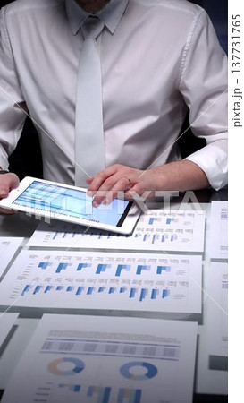 Businessman conducting detailed audit checking financial spreadsheets with tablet pc and charts on desk. Audit and taxes concept in business Businessman conducting detailed audit checking financial spreadsheets with tablet pc and charts on desk. Audit and taxes concept in business 137731765
