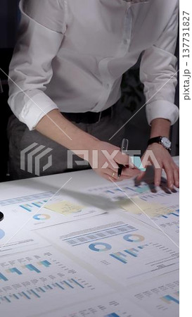 Business professional analyzing financial data and market statistics, calculating growth trends, making strategic decisions, and planning future investments on numerous charts at an office desk 137731827
