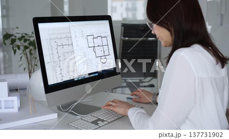 Woman architect drawing building plans on computer, designing modern housing project with cad software. Business and architecture concept Woman architect drawing building plans on computer, designing modern housing project with cad software. Business and architecture concept 137731902