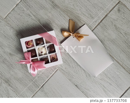 Delicious, sweet handmade chocolates made of white and milk chocolate with whole nuts in a gift box on a light background. High quality photo Delicious, sweet handmade chocolates made of white and milk chocolate with whole nuts in a gift box on a light background. High quality photo 137733708