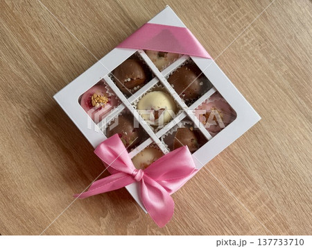 Delicious, sweet handmade chocolates made of white and milk chocolate with whole nuts in a gift box on a light background. High quality photo 137733710
