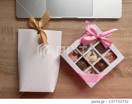 Delicious, sweet handmade chocolates made of white and milk chocolate with whole nuts in a gift box on a light background. High quality photo 137733732