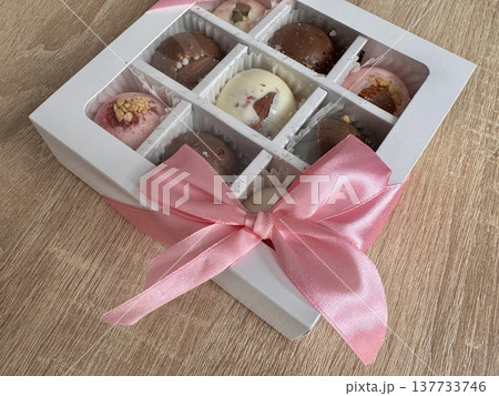 Delicious, sweet handmade chocolates made of white and milk chocolate with whole nuts in a gift box on a light background. High quality photo 137733746